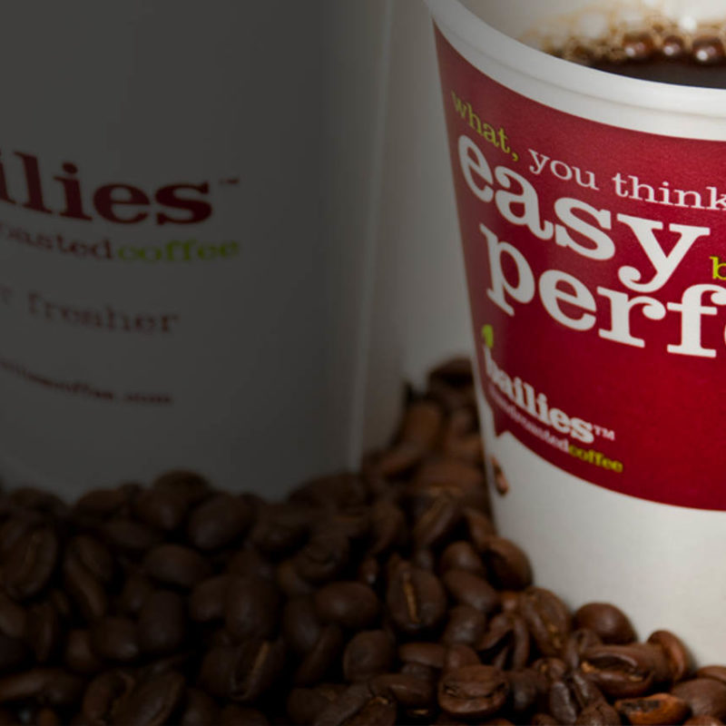 Bailies Coffee - coffee in a cup surrounded by roasted coffee beans